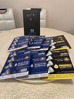Six sealed packages of Luminus LED GU10 50W dimmable light bulbs on a round table, showing front branding and bulb features.