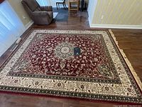 Full view of the red oriental rug showing the detailed floral pattern and medallion center, some missing fringe visible on one short edge