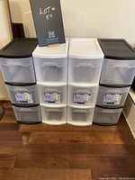 Four plastic storage bins arranged side by side, two black and two white.