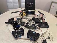 Photo showing the assortment of remote control helicopters and remote controllers, including charging adapters and cables, displayed on a table.