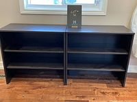 Photo showing both shelving units side by side against a wall under a window, highlighting their identical design and size.