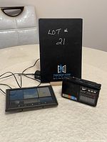 Vintage Golon RX 1315 transistor radio with Acu-Rite weather system placed on a surface; radio shows buttons and dials with a power cord, weather system shows screen with weather readings.