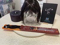 Dark brown wig on glass container with bangs and shoulder-length hair alongside 10 piece dark brown hair extensions in packaging.