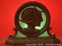 Front view of the antique Art Nouveau desk lamp showing the female profile bust in an oval frame, with a bronze tone and carved base.