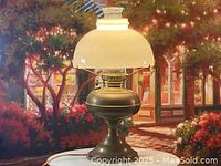 Full front view of the antique brass electrified kerosene lamp with milk glass shade, lit to show details.
