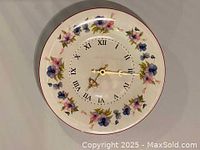 Front view of the Royal Vale porcelain wall clock showing the floral pattern, Roman numerals, and gold hands on a white background.