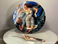 Set of a round 10.25 inch diameter cake plate and matching cake server with artistic painted design featuring a man and woman in a stylized scene.