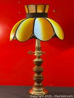 Full view of the Tiffany-style stained glass table lamp showing the yellow and milk glass shade and the brass and oak base with winding key detail