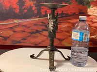 Side view of the vintage wrought iron horse head candle holder next to a water bottle for size reference