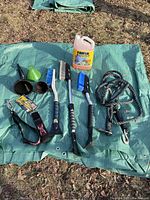 Overview of all automotive items on green tarp, including brushes, funnels, tow rope, straps, and Rain-X