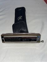 Weltmeister Double-Tuned Chromatic Professional harmonica with visible branding and included leather pouch on white cloth background.