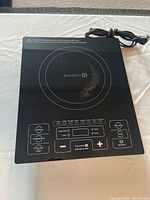 Top view of the Kuradori induction cooktop showing the control panel and worn spot on the cooking surface.