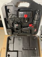 Jobmate cordless drill with 18V battery and charger inside black hard plastic case, alongside drill bits storage area visible.