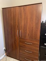 Closed large wooden wardrobe showing two doors and three drawers on the right side with silver curved handles.