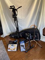Overall view showing three instrument stands, tin of straps and parts, footstool box and backpack guitar case