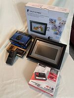 Photo showing Fidelity Electronics digital picture frame box and unit, Kingston SSD drive box, HP F210 car camcorder, and Genava micro cassette recorder with original box.