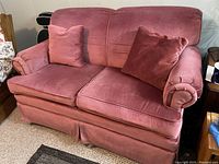 Front view of pink loveseat with two cushions on a carpeted floor