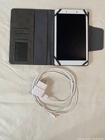 Samsung tablet in protective grey folio case with USB cable and charger laid out on surface.