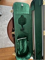 Open violin case showing green plush interior and molded shape for violin and bow pocket