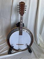 Front view of Weymann mandolin-banjo showing white drumhead, metal tone ring, wooden neck with inlaid fret markers