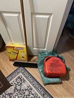 Full lot view showing gas can, green tarps, push broom, and boxed Coleman stove grate.