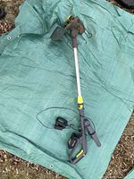 Full view of the Yardworks 20V cordless weed trimmer laid on a tarp, showing the weapon with the handle and shaft intact.