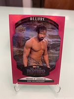 Front side of pink-bordered Marvel Allure Erik Killmonger trading card showing actor Michael B. Jordan as the character against a rocky backdrop.