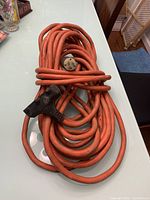 Coiled orange heavy duty extension cord with a molded 3-prong grounded plug and 3 grounded outlets.