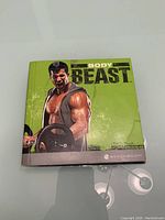 Closed view of the Body Beast DVD case with muscular man and green background on front cover