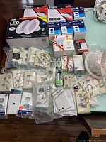 Photo showing the array of boxed LED retrofit lighting kits, multiple bulb packages, boxed switches, and electrical accessories spread on a table.