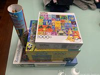 Stacked puzzles and a cylinder container with pick up sticks on a flat surface