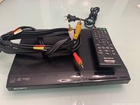 Sony DVD player top and front view with remote and AV cables placed on top