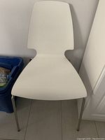 Front view of white modern chair with curved seat and backrest and thin metal legs