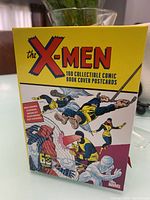 Full view of the front of the yellow box featuring classic X-Men comic art with the title and number of postcards inside