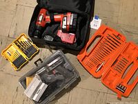 Black & Decker Bulls Eye cordless drill with battery and charger next to Dewalt and Black & Decker drill bit cases, plus clear case holding Weller soldering tool