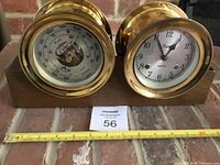 Front view of both brass instruments on wooden stand with measuring tape for scale