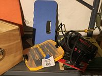 Photo showing Craftsman 3/8 drill, yellow Dewalt drill bit case with bits inside, blue knee pad and an orange knee pad in background