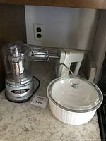 Photo showing Cuisinart Mini Prep food processor, Black & Decker hand mixer, and white covered casserole dish on kitchen counter.