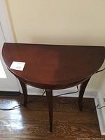 Top down view of the half moon shaped dark wood table showing its smooth surface and semi-circular shape.