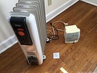 DeLonghi oil-filled radiator heater and Honeywell small space heater side by side on wood floor