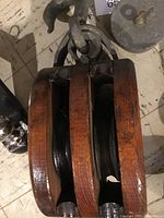 Close-up of a wooden pulley block with three grooves and metal hooks