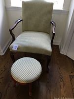 Full view of Queen Anne style armchair with soft green and white plaid upholstery and wooden arms, alongside matching footstool with same fabric and wooden legs.