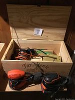Photo of the wooden storage box containing a Black and Decker drill and two hand sanders (square and circular)