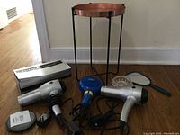 Entire vanity lot showing two Revlon Tourmaline Ceramic Ionic hair dryers, one blue Wave Rage hair dryer, two handheld mirrors, jewelry dish, and small metal stand with copper top