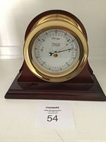 Front view of barometer showing brass bezel, white dial marked Weems & Plath, and wood base.