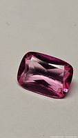 Close-up front view of the cushion cut hot pink topaz gemstone showing facets and color.