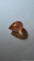 Photo showing a 1.07ct natural padparadcha sapphire with a peach color and briolette cut.