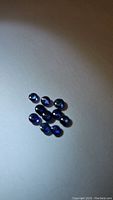 Ten natural round cabochon royal blue sapphire gemstones arranged on a white background, showing size and color consistency.
