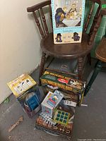 Full overview of the lot showing all items arranged at the base of a wooden chair with the boxed Paddington Bear dinnerware set on the seat.