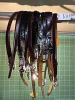 Belts hanging on a rod, various colors and sizes visible, buckles wrapped in plastic.